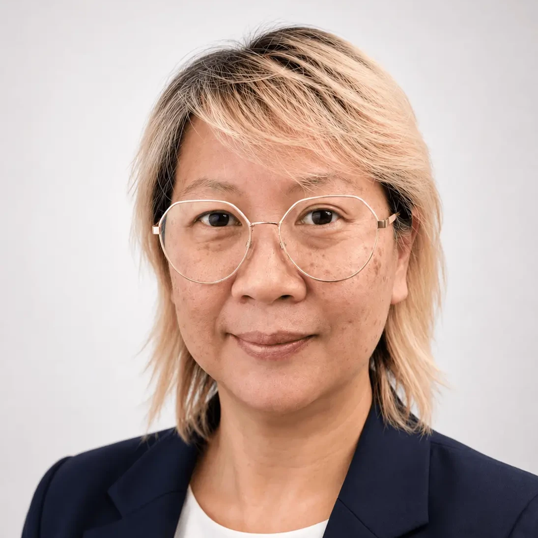 Wee See Chua wearing round glasses and a navy blazer against a light background.